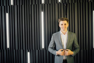 Modern ofis ahşap karanlık duvara iş takım elbiseli yakışıklı bir genç adam portresi