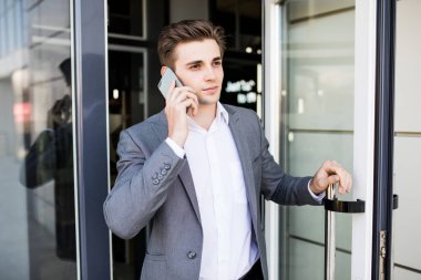Office kapı ve beyaz dışında olsun telefonla konuşmak tutan genç iş adamı