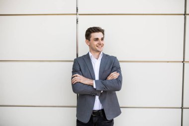 Açık havada arka planda ofis binaları ile çapraz el ile ayakta işadamı