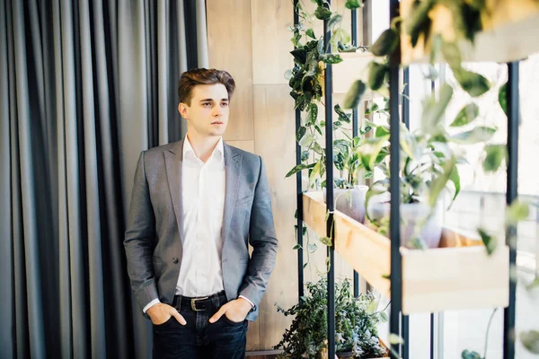 Bonito homem de negócios jovem em sala de escritório moderno olhando para longe na janela — Fotografia de Stock
