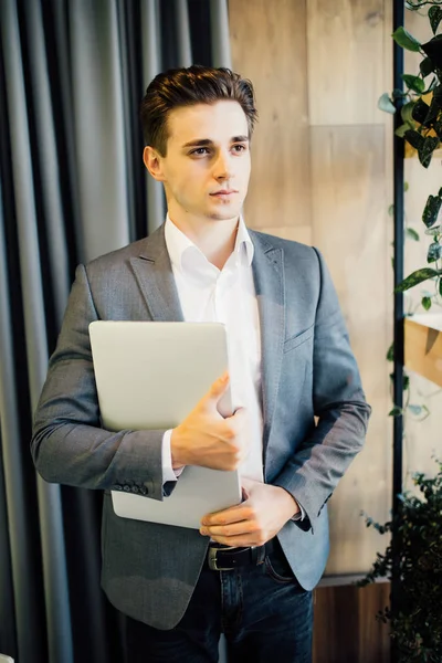 Mladý podnikatel s přenosným počítačem v rukou chodit v moderní kanceláři — Stock fotografie