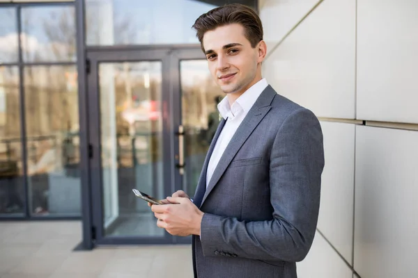 Un hombre mandando mensajes por teléfono. Empresario profesional urbano casual usando teléfono inteligente sonriendo feliz fuera del edificio de oficinas . — Foto de Stock