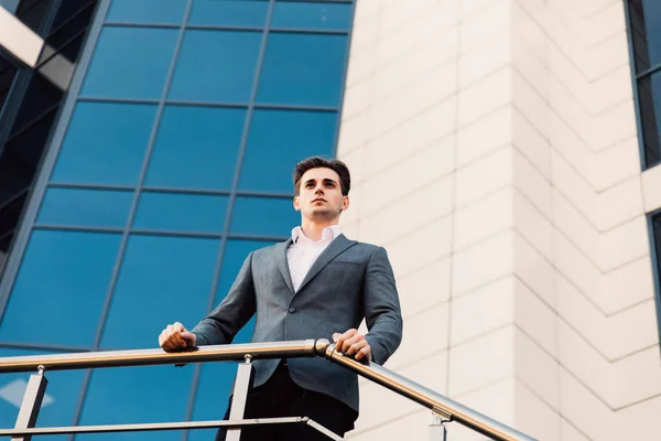 Atractivo joven empresario frente a un moderno edificio de oficinas en un hermoso día soleado . — Foto de Stock