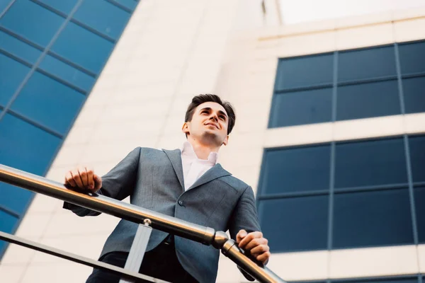 Feliz hombre de negocios sonriente usando traje cerca de la oficina en la mañana temprano, empleador exitoso para hacer un trato mientras está de pie cerca de la oficina de rascacielos — Foto de Stock