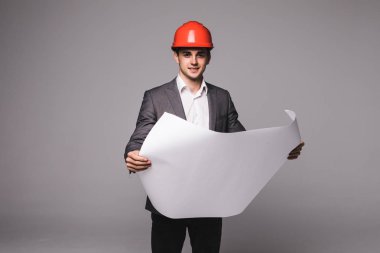 Klasik takım elbise ve koruyucu kask çekici işadamı haddelenmiş kağıt, gri arka plan üzerinde tutuyor