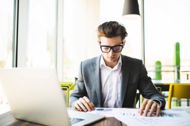 İşadamı ofisinde masasının üzerindeki laptop, tablet ve grafik veri belgelerle çalışma.