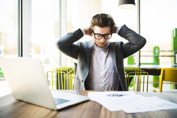 Young man working with laptop at home browsing bills and documents