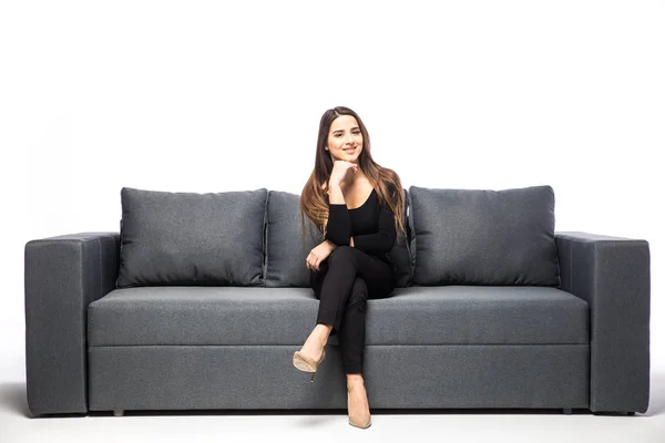 Giovane donna seduta su un divano e guardando nella fotocamera isolata su sfondo bianco — Foto Stock