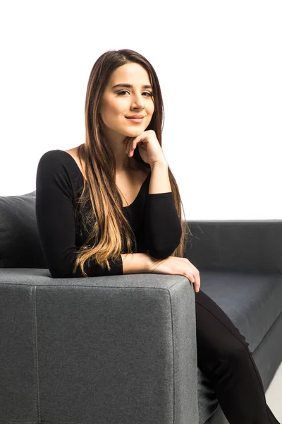 Портрет щасливої молодої жінки, що сидить на дивані на білому тлі — стокове фото