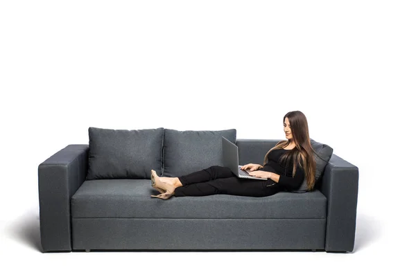 Woman lying on sofa at home working on laptop computer. Isolated on white background. — Stock Photo, Image