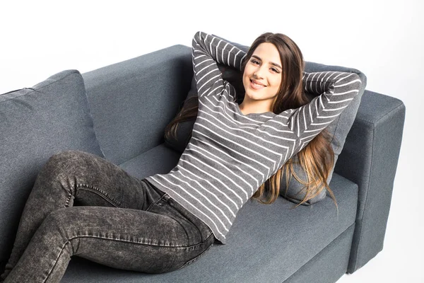 Жінка розслабляється сидячи на дивані з руками на голові на білому тлі — стокове фото
