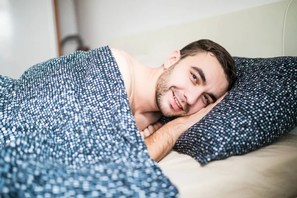 Молодой человек счастлив спать в теплой постели дома — стоковое фото