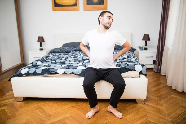 Frustrado cara sente dor nas costas na cama de manhã — Fotografia de Stock