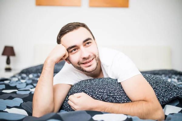 Красивый мужчина смеется, лежа на кровати — стоковое фото