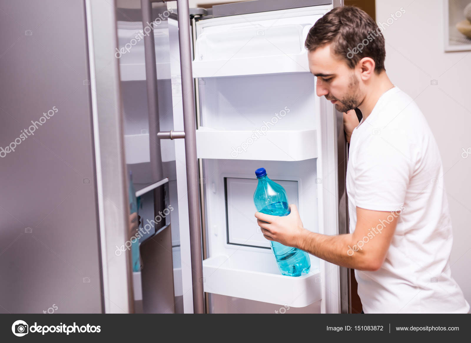 Man open refrigerator door and get water in the kitchen at home — Stock