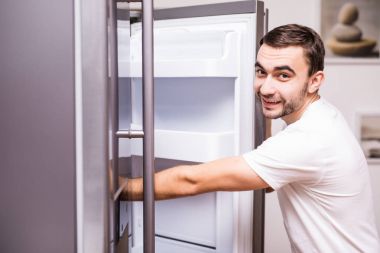 Adam açık buzdolabı kapı ve arama gıda mutfak ev