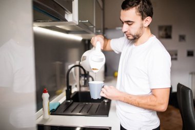 Adam mutfakta bir fincan sıcak kahve cam aranjman dökme. Sabahları kahvaltı