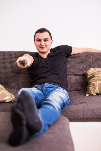 Young handsome man watching TV on a sofa at home — Stock Photo, Image