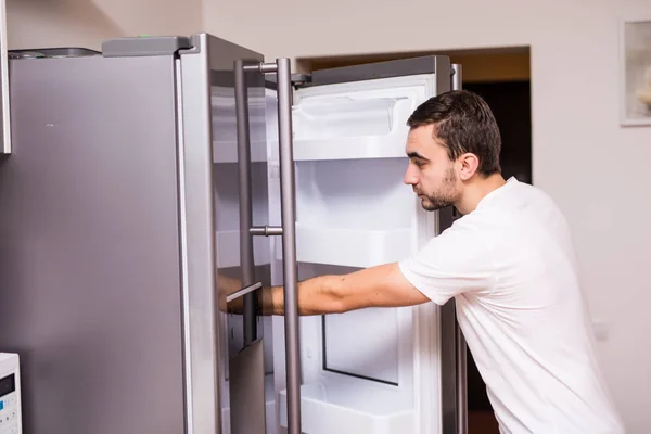 Man open refrigerator door in the kitchen at home