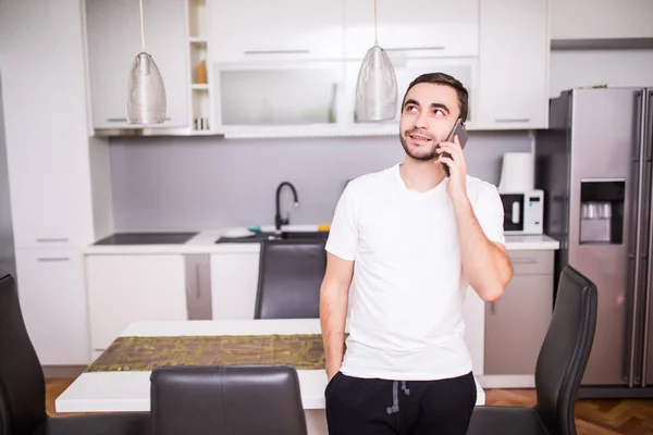 Homem falando no celular na cozinha em casa pela manhã — Fotografia de Stock