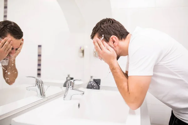 Jasny kaukaski mężczyzna rozpylanie wody na jego twarzy w łazience w domu — Zdjęcie stockowe