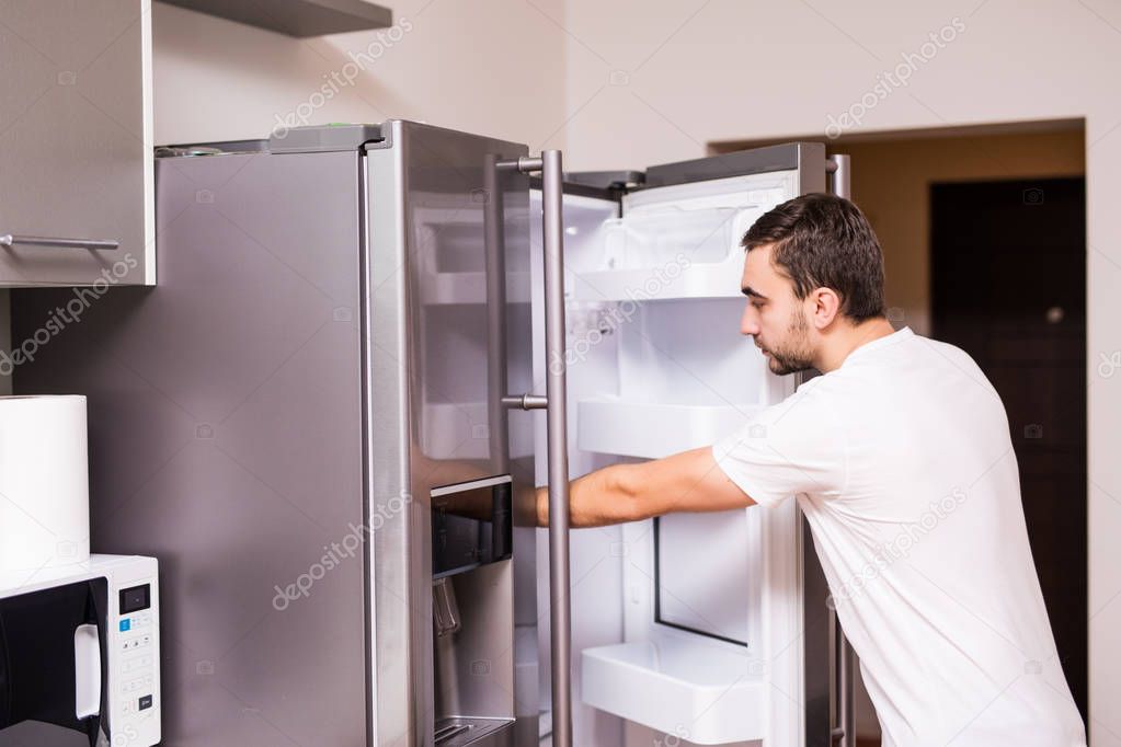 Man open refrigerator door in the kitchen at home