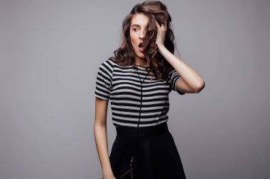 Kıvırcık saçlı ve gri arka plan üzerinde poz doğal makyaj moda modelinin duygusal portre.