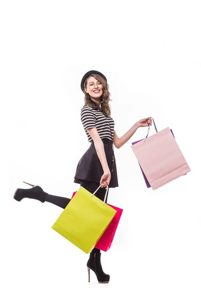 Vista laterale a tutta lunghezza della giovane donna che cammina con shopping bag isolato su sfondo bianco — Foto Stock