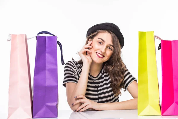 Young beautiful young woman with shopping bags on table satisfied and have rest with happy smile on white background — Stock Photo, Image