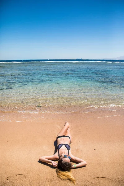 Молодая женщина лежит на пляже у воды — стоковое фото