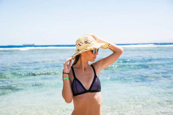 Mulher de chapéu e óculos de sol na praia com fundo do mar — Fotografia de Stock