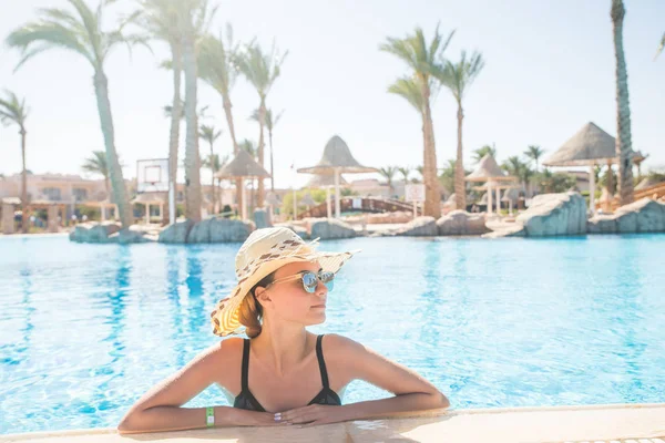 Милая девушка в шляпе и солнцезащитных очках в бассейне с копировальным пространством. Летнее призвание . — стоковое фото