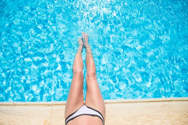 Felülnézet fiatal nő napozó medence közelében. Felülnézet lábak medence közelében — Stock Fotó