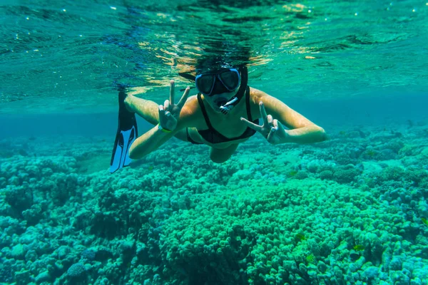 Kobieta pod wodą z rurką wgesturing zwycięstwo pływanie w morzu — Zdjęcie stockowe