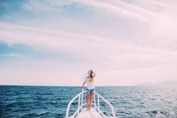 Hermosa hembra de pie en la nariz del yate en el océano en un día soleado de verano — Foto de Stock