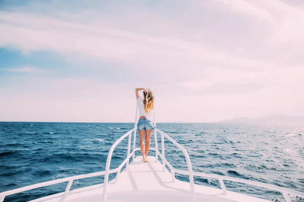 Bella femmina in piedi sul naso dello yacht in mare in una giornata estiva soleggiata — Foto Stock