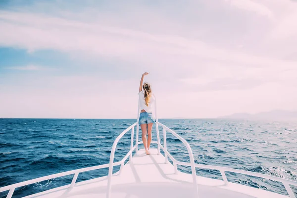 Красивая женщина, стоящая на носу яхты в солнечный летний день, бриз развивающиеся волосы, красивое море на заднем плане — стоковое фото