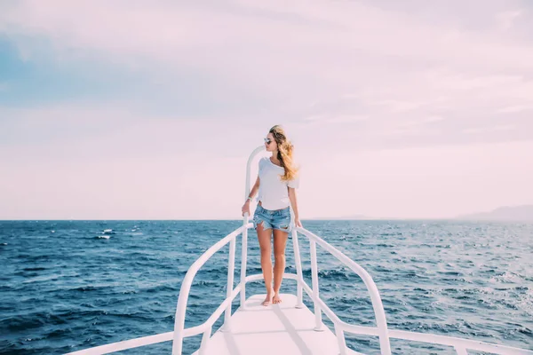 Hermosa hembra de pie en la nariz del yate en el océano en un día soleado de verano —  Fotos de Stock