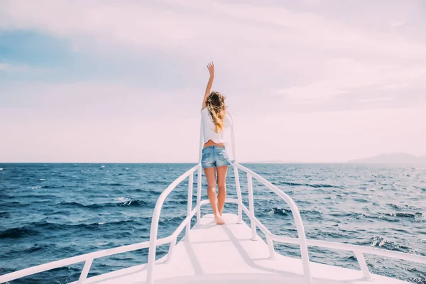 Красавица, стоящая на носу яхты на фоне моря — стоковое фото