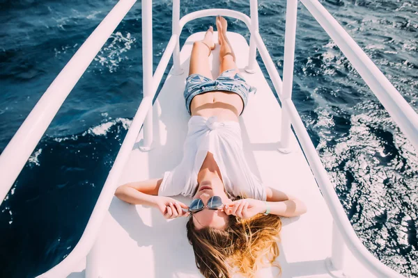 Girl lying on yacht deck. Smiling lady in swimsuit. Relax and enjoy your vacation.
