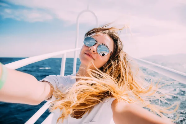 Молодая женщина делает селфи на яхте, плавающей в море — стоковое фото