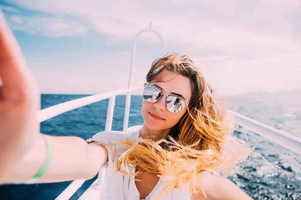 Mujer joven tomando selfie t en el yate flotando en el mar —  Fotos de Stock