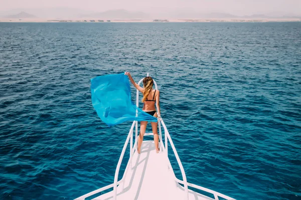 Hermosa mujer en la nariz del yate con la onda bufanda azul en el viento. vocación hora de verano en yate . — Foto de Stock