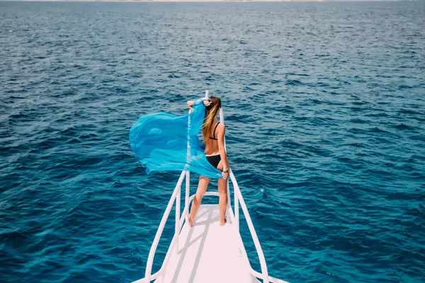 Mujer en la nariz del yate con la onda bufanda azul en el viento. vocación hora de verano en yate . — Foto de Stock