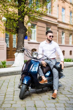 yakışıklı genç adam sokakta vintage bir scooter sürme
