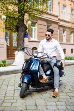 Yakışıklı adam eski şehir scooter üzerinde seyahat
