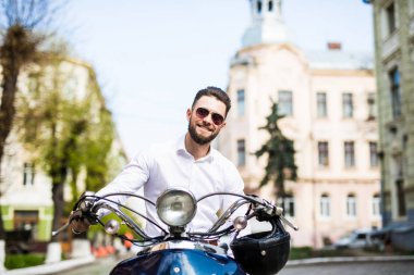 Yakışıklı genç işadamı binme scooter sokak kasabanın içinden