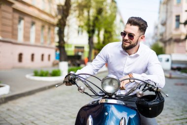 Handsome happy man riding a motorbike on street clipart