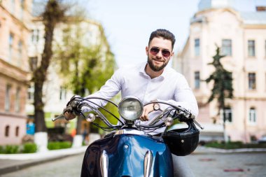 Scooter üzerinde otururken yakışıklı genç