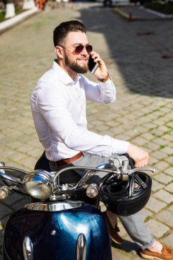 Şehir telefonda konuşurken sokak motosiklet üzerinde oturan yakışıklı adam